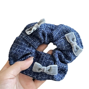 Elegant deep blue tweed scrunchie with grey velvet bows held against white background