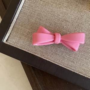 Barrette à cheveux nœud rose en résine acrylique brillante sur plateau tissé