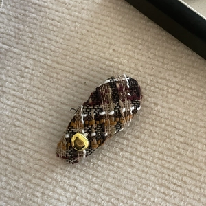 Close-up of vintage brown tweed plaid hair clip featuring a refined gold metal button