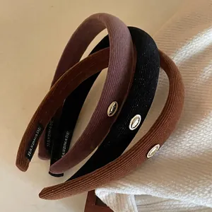 Three-piece set of corduroy padded headbands in purple, black, and brown with gold detail