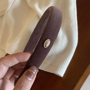 Deep brown corduroy padded headband with a gold metal emblem for women's hair styling
