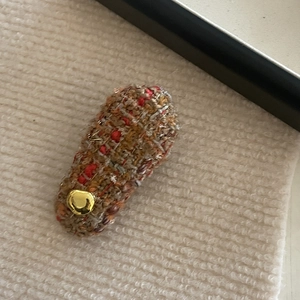 Detail of tweed fabric hair clip with a vintage gold button and elegant woven pattern