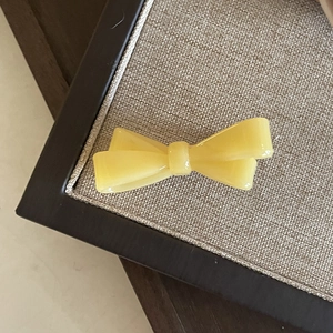 Détail d'une pince à cheveux nœud en résine jaune vif sur un plateau de présentation