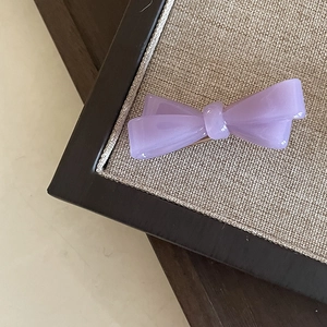 Gros plan d'une barrette à cheveux nœud en acrylique lilas avec finition nacrée
