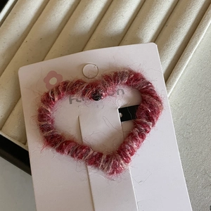 Detail of red and cream knitted heart hair clip with a cozy plush wool texture