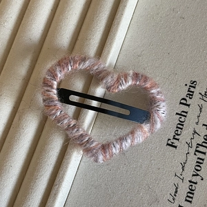 Close-up of pink and white knitted heart-shaped hair clip with metal BB grip