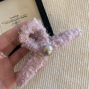 Détail de la pince à cheveux en peluche rose avec fils dorés et perle argentée centrale
