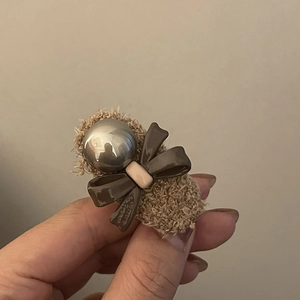 Detail of a brown faux fur bow hair clip with a silver metallic sphere decoration