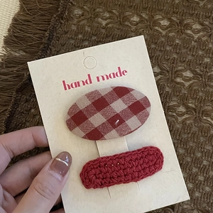 Detail of red handmade crochet hairpin and checkered clip set on a display card
