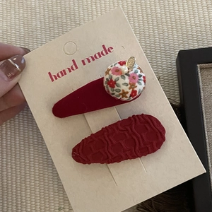 Detail of dark red festive bow hair clips with floral fabric ball and pearl decoration