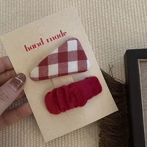Festive red fabric hair clip set with plaid and solid designs on a gift card