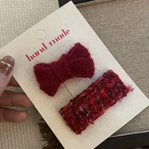 Detail of handmade festive red knitted bow and sequin hair clip set on display card
