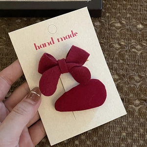 Detail of red velvet handmade bow and hair clip set on a decorative paper card