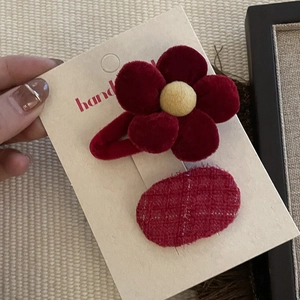 Detailed view of handmade red velvet flower clip and red checkered fabric hair accessories