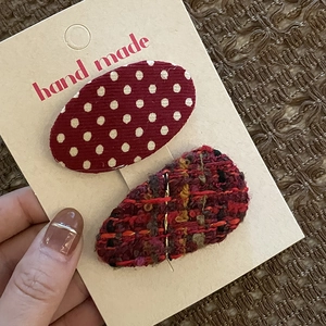 Close-up of handmade red bow hair clips with polka dots and tweed texture on display card