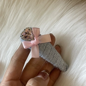 Gros plan sur la barrette en tricot bleu avec nœud rose et strass en forme de cœur