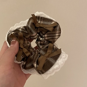 Plaid hair scrunchie with white lace trim and brown satin bows held in hand