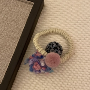 Colorful pom pom hair tie with faux fur and polka dot yarn balls on beige elastic band