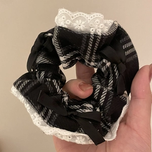 Detailed close-up of a black and white plaid scrunchie with lace trim and small bows