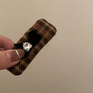 Brown plaid hair clip with black bow and heart crystal in a soft handheld display