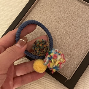 Detailed close-up of handmade yarn ball hair ties with colorful fuzzy pom pom accents