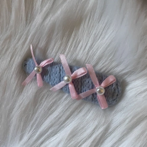 Barrette en tricot bleu avec nœuds roses et perles blanches sur fond de fourrure blanche