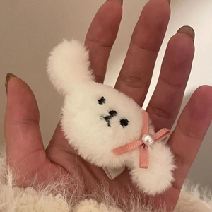 Détail de la pince à cheveux en peluche blanche avec nœud rose et perle