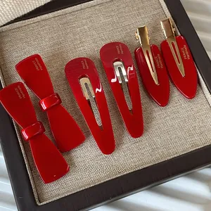 Détail de barrettes à cheveux en acétate rouge avec base en métal doré et gravure