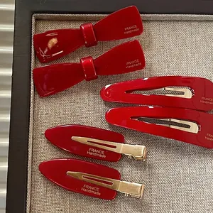 Coffret de barrettes à cheveux en acétate rouge vin avec nœuds et clips sur un plateau