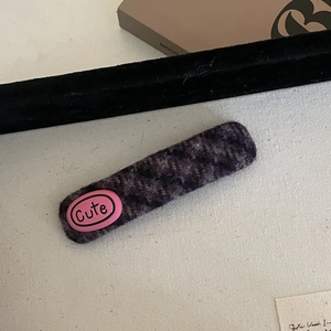 Close-up of a purple tweed checkered hair clip featuring a pink Cute label detail
