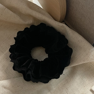 Detailed view of vintage black velvet scrunchie with lace texture on beige linen cloth