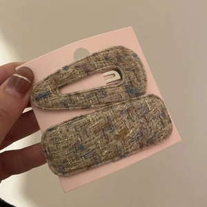 Detail of tweed hair clips set with gold thread weaving on a pink display card