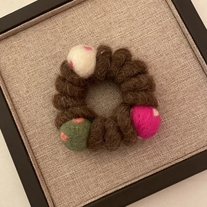 Détail de l'élastique spirale en laine marron avec boules de feutre à pois colorés