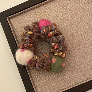 Détail d'un élastique arc-en-ciel en laine tricotée avec des boules de feutre colorées