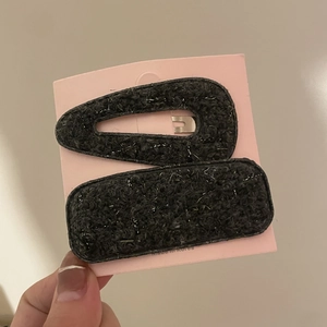 Close-up of black wool fabric hair clips set with silver threads on display card