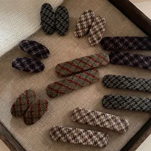 Detailed view of assorted vintage plaid fabric hair clips on a linen display tray