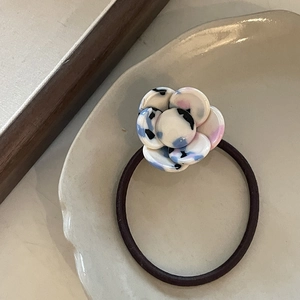Elegant camellia hair tie with blue pink artistic acetate flower on a ceramic plate