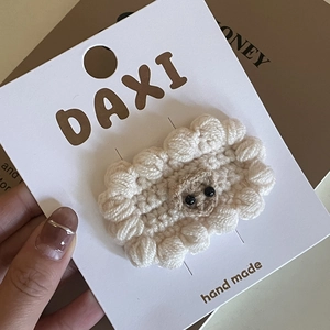 Detaillierte Makroansicht der handgehäkelten Lamm-Haarspange aus beige-weißem Garn
