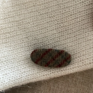 Vintage red plaid fabric hair clip with a white plush base and striped oval texture