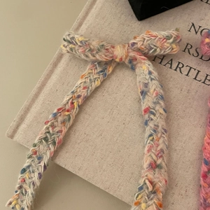 Detailaufnahme einer weißen Strickschleife Haarspange mit bunter gesprenkelter Wolltextur