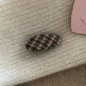 Retro houndstooth fabric hair clip displayed on soft white knit background for autumn
