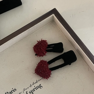 Detailed view of two vintage red plush heart-shaped hair clips on a cream display tray