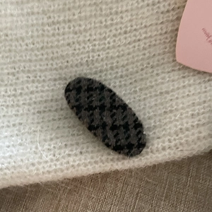 Detail shot of vintage houndstooth fabric hair clip on soft white knit texture