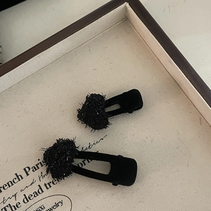 Close-up of black heart-shaped hair clips with sparkling textured wool and sequins