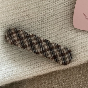 Close-up of vintage brown plaid fabric hair clip on soft knit texture background