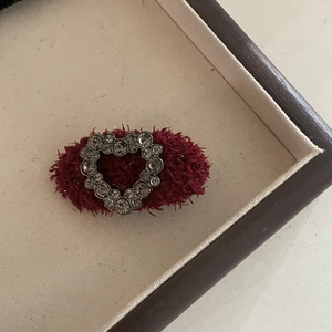 Detailed view of dark red wool fabric hair clip with center heart crystal decoration