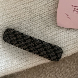 Detail shot of rectangular hair clip featuring grey houndstooth pattern fabric on soft knit