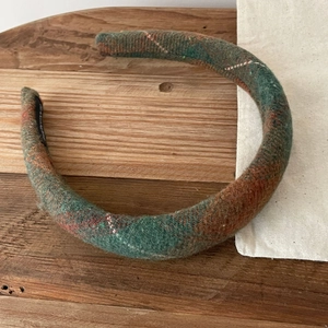 British style green and orange plaid headband made of thick tweed fabric on a wooden surface