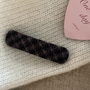 Close-up of a retro dark grey velvet rectangular hair clip on a cozy knit background