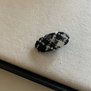 Elegant Korean style oval hair clip with black and white tweed fabric on beige surface